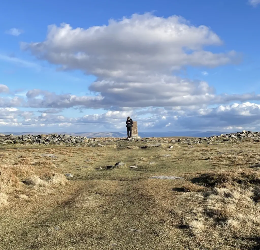 A hiker stood at the cairn on High Street